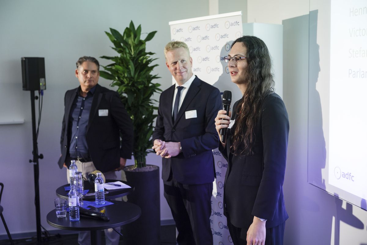 Stefan Zierke MdB, Henning Rehbaum (MdB) und Victoria Broßart MdB von Parlamentskreis Fahrrad stehen auf der Bühne, Broßart mit Mikrofon in der Hand. 